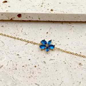 Bracelet doré en acier avec pendentif fleur en verre bleu.