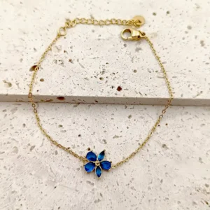 Bracelet doré en acier avec pendentif fleur en verre bleu.