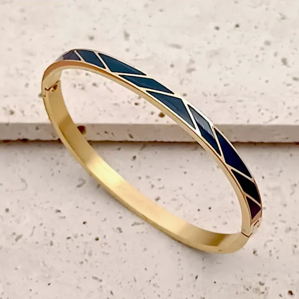 Bracelet jonc en acier doré, fermé, orné d’un motif émaillé noir en zigzag.
