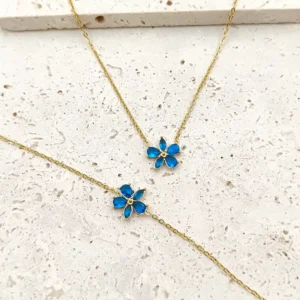 Colliers et bracelets assortis dorés en acier avec pendentif fleur en verre bleu.