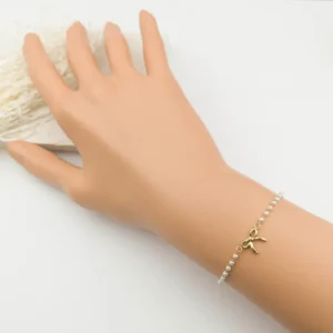 Bracelet en acier doré avec perles blanches nacrées et pendentif nœud – bijou fin et élégant pour femme