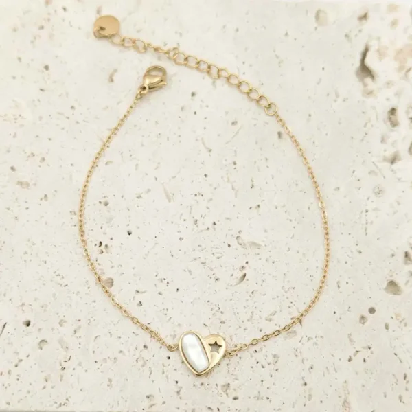 Bracelet fin en acier inoxydable doré, orné d’un pendentif cœur en nacre blanche avec une étoile ajourée.