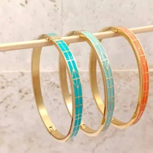 Ensemble de trois bracelets joncs en acier doré, décorés d’émaux colorés cyan, turquoise et orange avec motifs de flèches stylisées