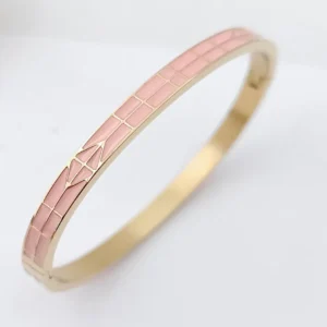 Bracelet jonc doré avec émaux roses et motif flèche stylisée.