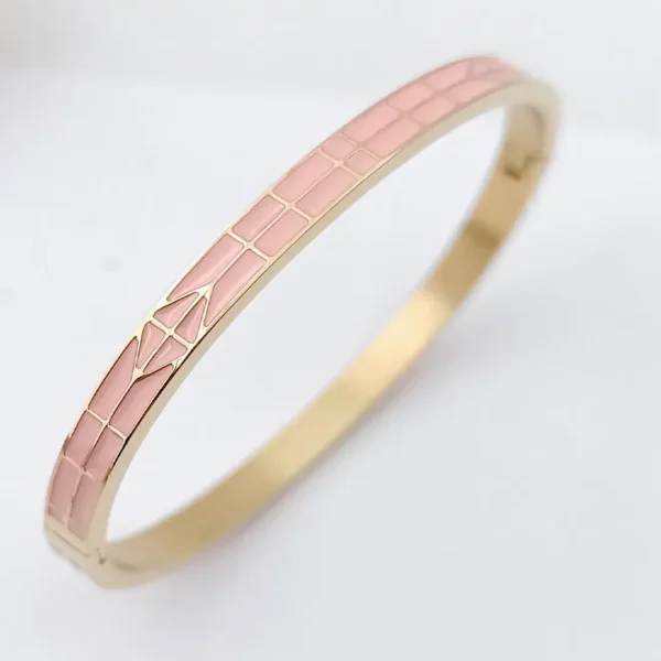 Bracelet jonc doré avec émaux roses et motif flèche stylisée.