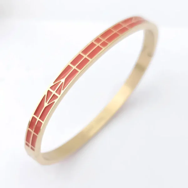 Bracelet jonc doré avec émaux couleur corail et motif flèche stylisée.
