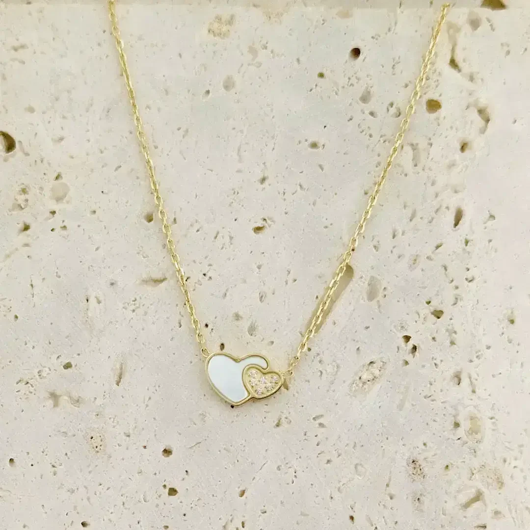 Collier mode femme en acier inoxydable doré, double cœur élégant avec nacre blanche et strass brillant.