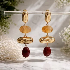 Boucles d’oreilles pendantes en acier doré avec perles en résine marron clair et marron foncé, au design élégant et contemporain.