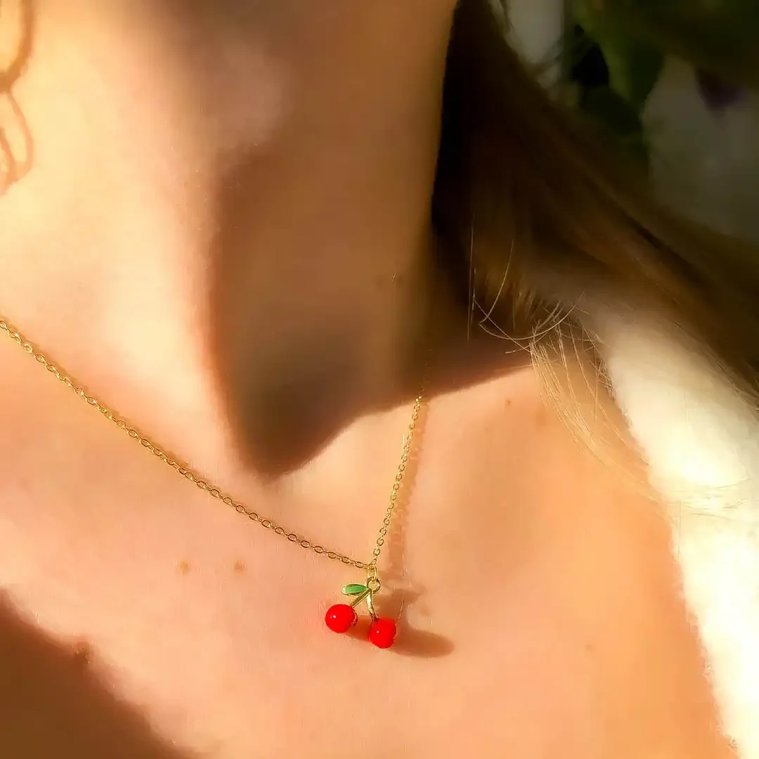 Collier acier doré avec pendentif en forme de cerise rouge et feuille verte émaillées