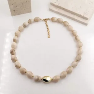 Collier acier en perles beiges irrégulières avec fermoir doré et perle centrale ovale dorée, bijou raffiné en résine.