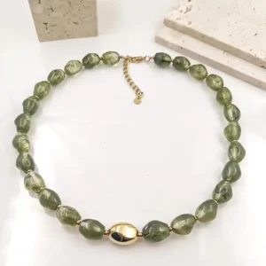 Collier acier en perles vertes irrégulières avec fermoir doré et perle centrale ovale dorée, bijou raffiné en résine.