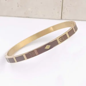 Bracelet jonc acier doré et émaillé marron foncé . Gravure doré