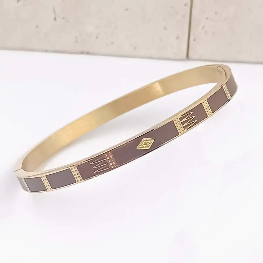 Bracelet jonc acier doré et émaillé marron foncé . Gravure doré