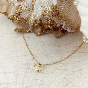 Collier en acier inoxydable doré avec pendentif cœur ajouré et petit cœur central.