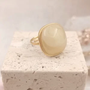 Bague ajustable en acier doré avec pierre en résine ivoire aux reflets doux.