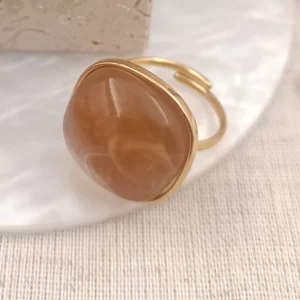 Bague ajustable en acier doré avec pierre en résine marron aux reflets doux.