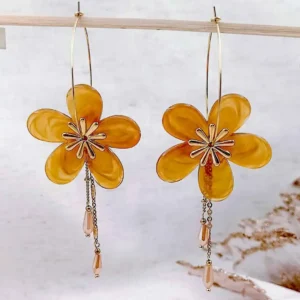 Boucles d’oreilles créoles dorées avec fleurs en résine couleur miel et pampilles délicates, bijou élégant et féminin.