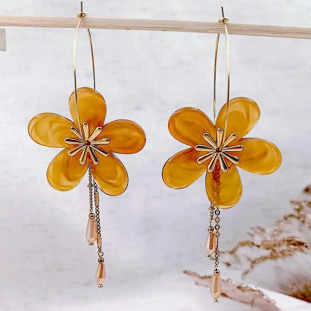 Boucles d’oreilles créoles dorées avec fleurs en résine couleur miel et pampilles délicates, bijou élégant et féminin.