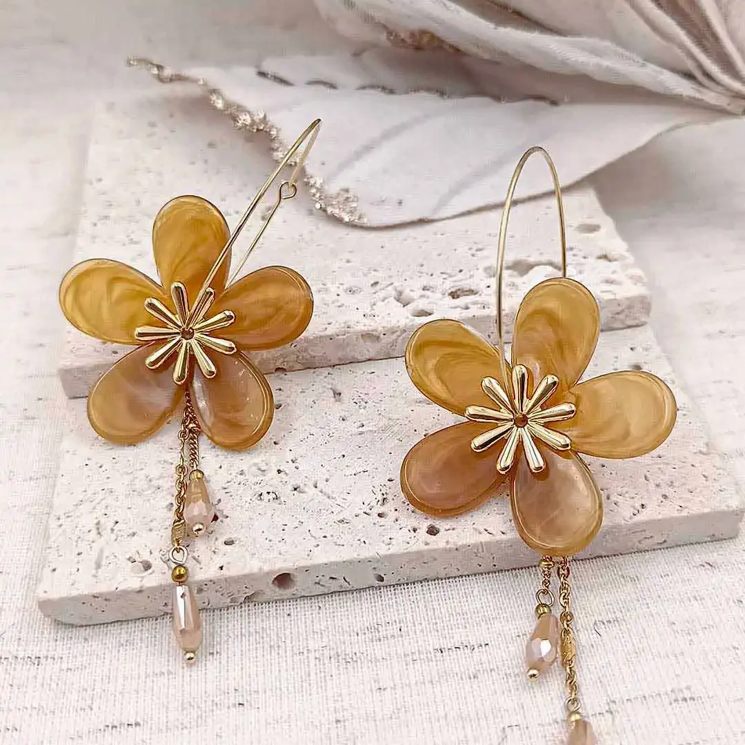 Boucles d’oreilles créoles dorées avec fleurs en résine couleur miel et pampilles délicates, bijou élégant et féminin.