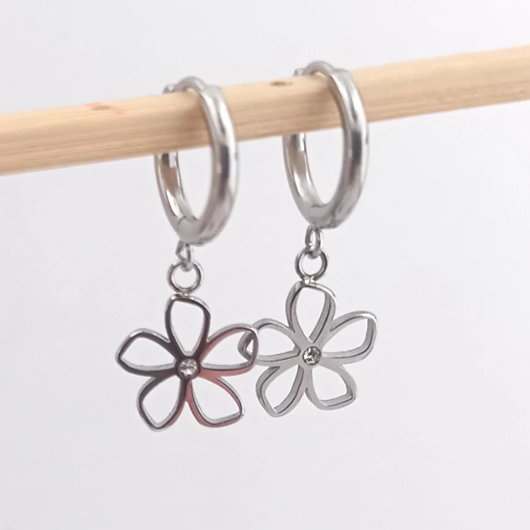 Boucles d’oreilles mini créoles en acier inoxydable avec pendentif fleur et petit strass central, finition argent.