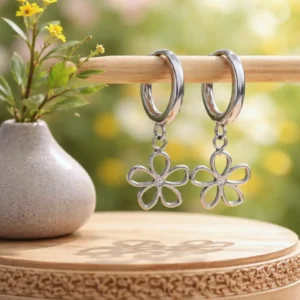 Boucles d’oreilles mini créoles en acier inoxydable avec pendentif fleur et petit strass central, finition argent.