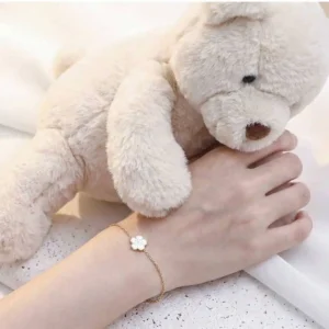 Bracelet enfant en acier inoxydable doré avec fleur émaillée de couleur blanche.