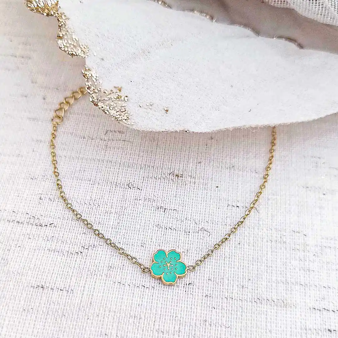 Bracelet enfant en acier inoxydable doré avec fleur émaillée de couleur bleue.