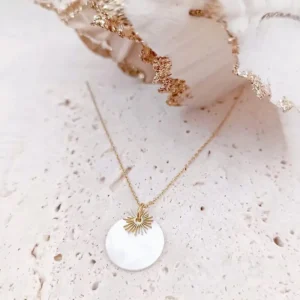 Collier fin en acier doré orné d’un pendentif rond en nacre avec un délicat motif soleil.