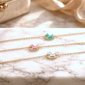 Bracelet enfant en acier doré avec pendentif cheval à bascule émaillé rose, bleu et blanc