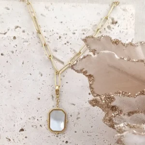 Charm rectangulaire en acier inoxydable doré avec insert en nacre blanche, finition vintage et fermoir mousqueton.