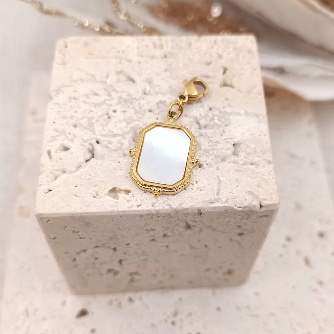 Charm rectangulaire en acier inoxydable doré avec insert en nacre blanche, finition vintage et fermoir mousqueton.