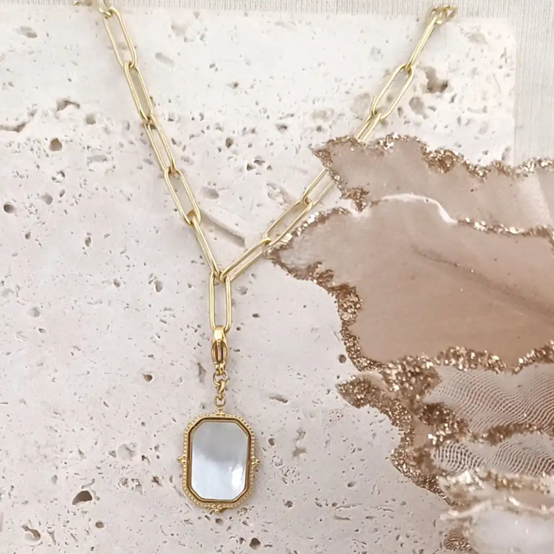 Charm rectangulaire en acier inoxydable doré avec insert en nacre blanche, finition vintage et fermoir mousqueton.