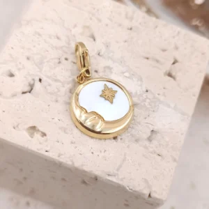 Charm personnalisé rond en acier inoxydable doré avec nacre blanche et motifs lune et étoile dorées, fermoir mousqueton intégré.