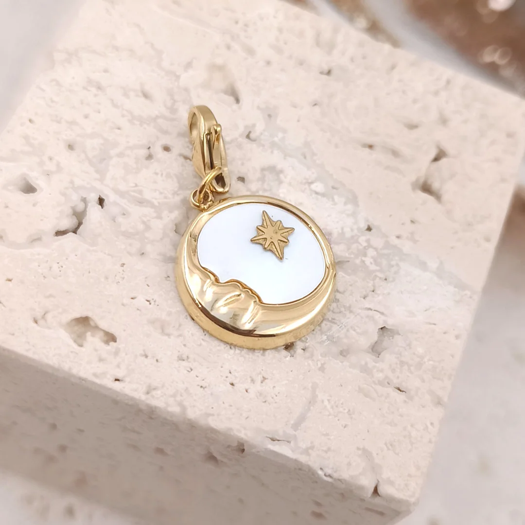 Charm personnalisé rond en acier inoxydable doré avec nacre blanche et motifs lune et étoile dorées, fermoir mousqueton intégré.
