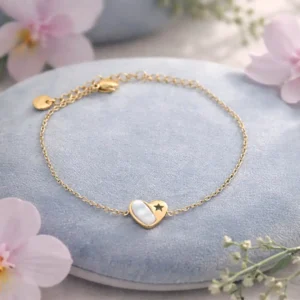 Bracelet fin en acier inoxydable doré, orné d’un pendentif cœur en nacre blanche avec une étoile ajourée.