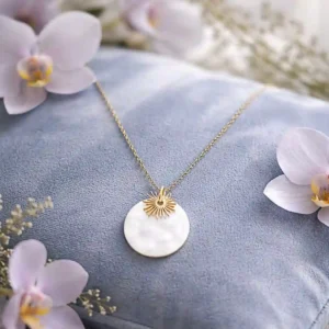 Collier fin en acier doré orné d’un pendentif rond en nacre avec un délicat motif soleil.