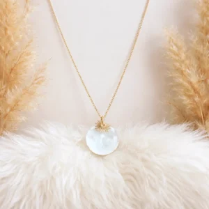 Collier fin en acier doré orné d’un pendentif rond en nacre avec un délicat motif soleil.