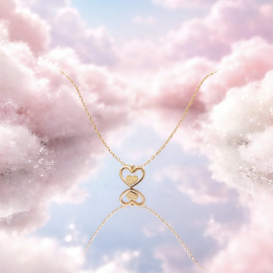 Collier en acier inoxydable doré avec pendentif cœur ajouré et petit cœur central.