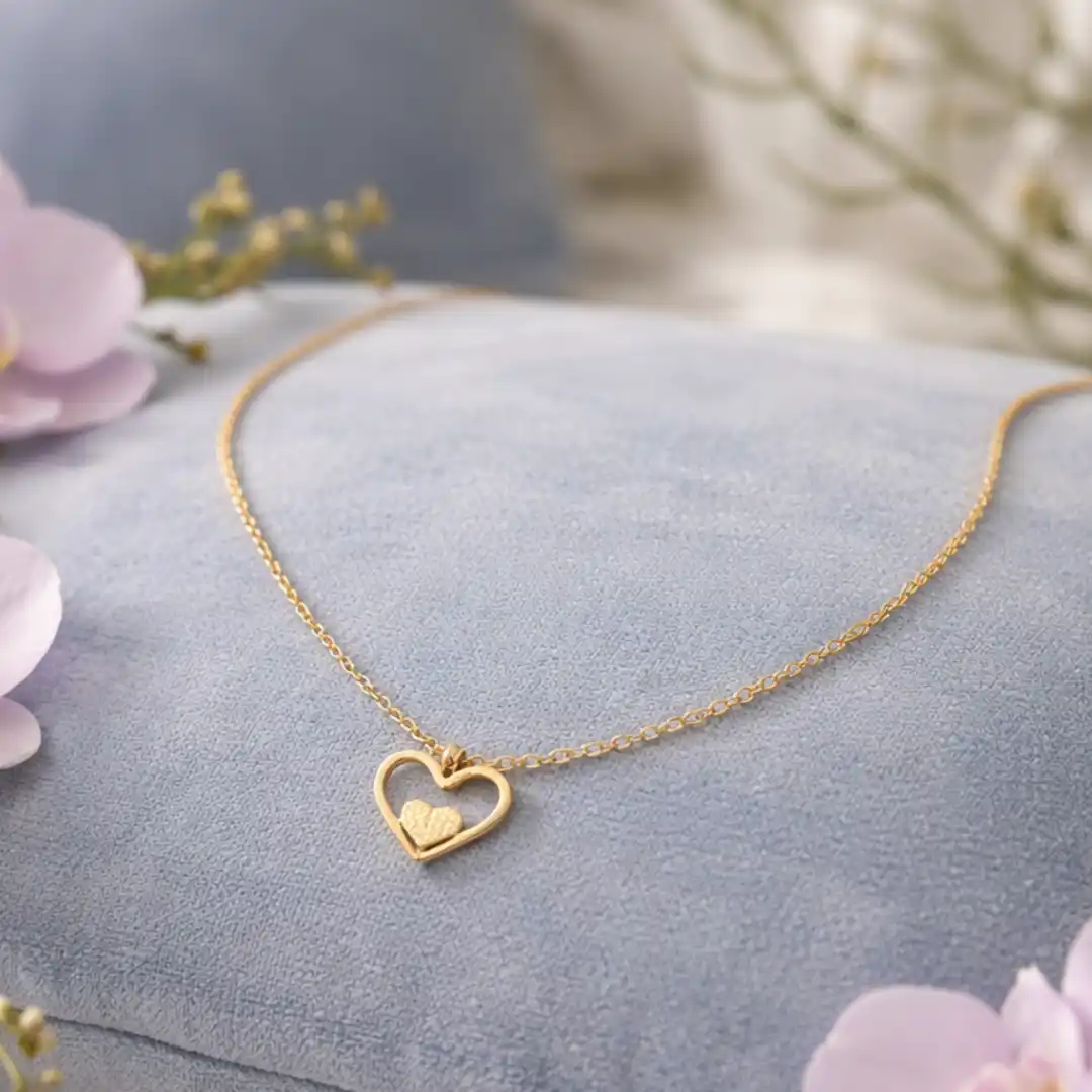 Collier en acier inoxydable doré avec pendentif cœur ajouré et petit cœur central.