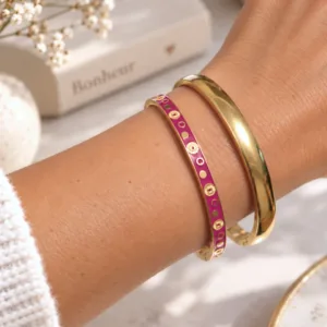 Bracelet jonc émaillé femme fuchsia porté en accumulation avec un jonc doré