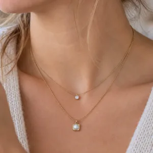 Collier multirang doré porté avec pendentif carré en nacre blanche
