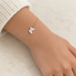 Détail du papillon blanc aux contours dorés sur un bracelet enfant en acier inoxydable à chaîne fine