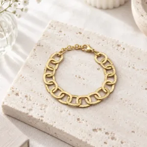 Bracelet doré à gros maillons carrés texturés et entrelacés, avec fermoir mousqueton et chaînette d'extension.