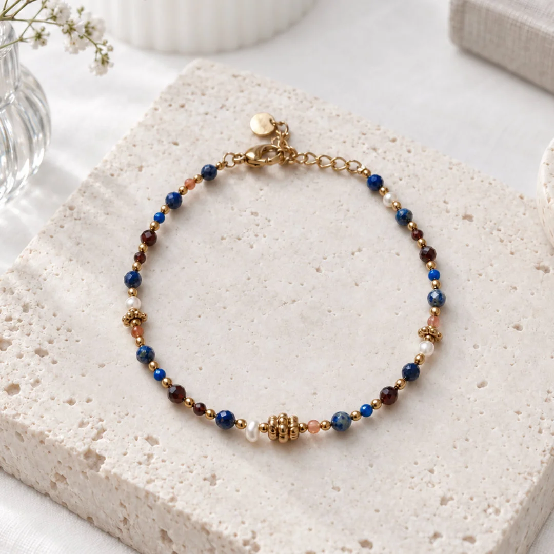 Bracelet petites pierres bleues et perles dorées en acier inoxydable, avec perles brunes et blanches, fermoir mousqueton et chaînette d'extension.