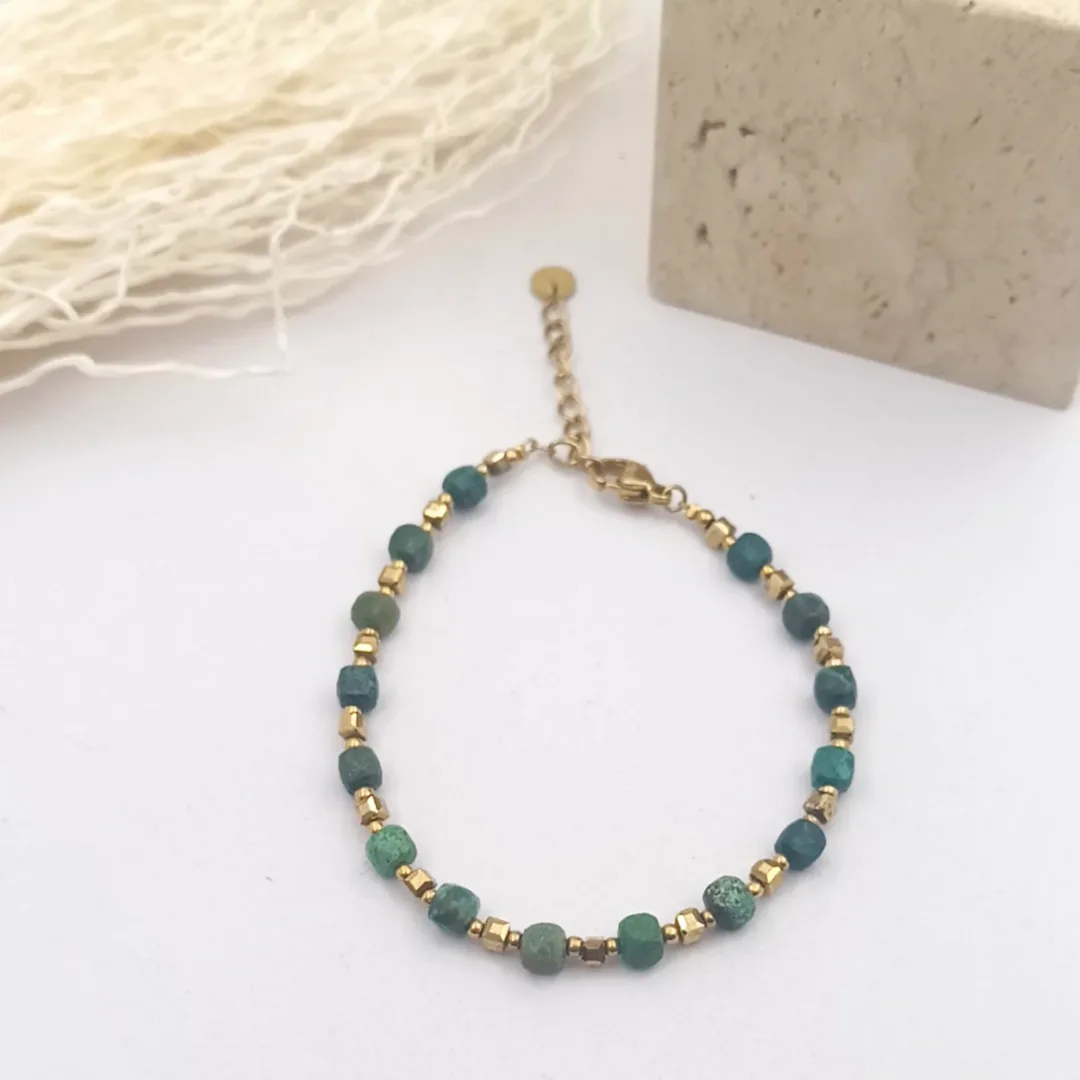 Bracelet femme à petites pierres vertes cubiques et intercalaires dorés, avec fermoir mousqueton et chaînette d'extension.