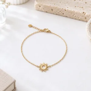 Bracelet fin doré en acier inoxydable avec motif soleil ajouré au centre et chaîne délicate réglable.