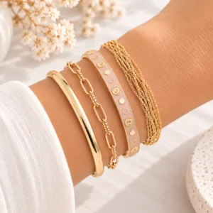 Accumulation de bracelets femme dorés avec jonc émaillé rose, bracelet à maillons et bracelet multi-rangs